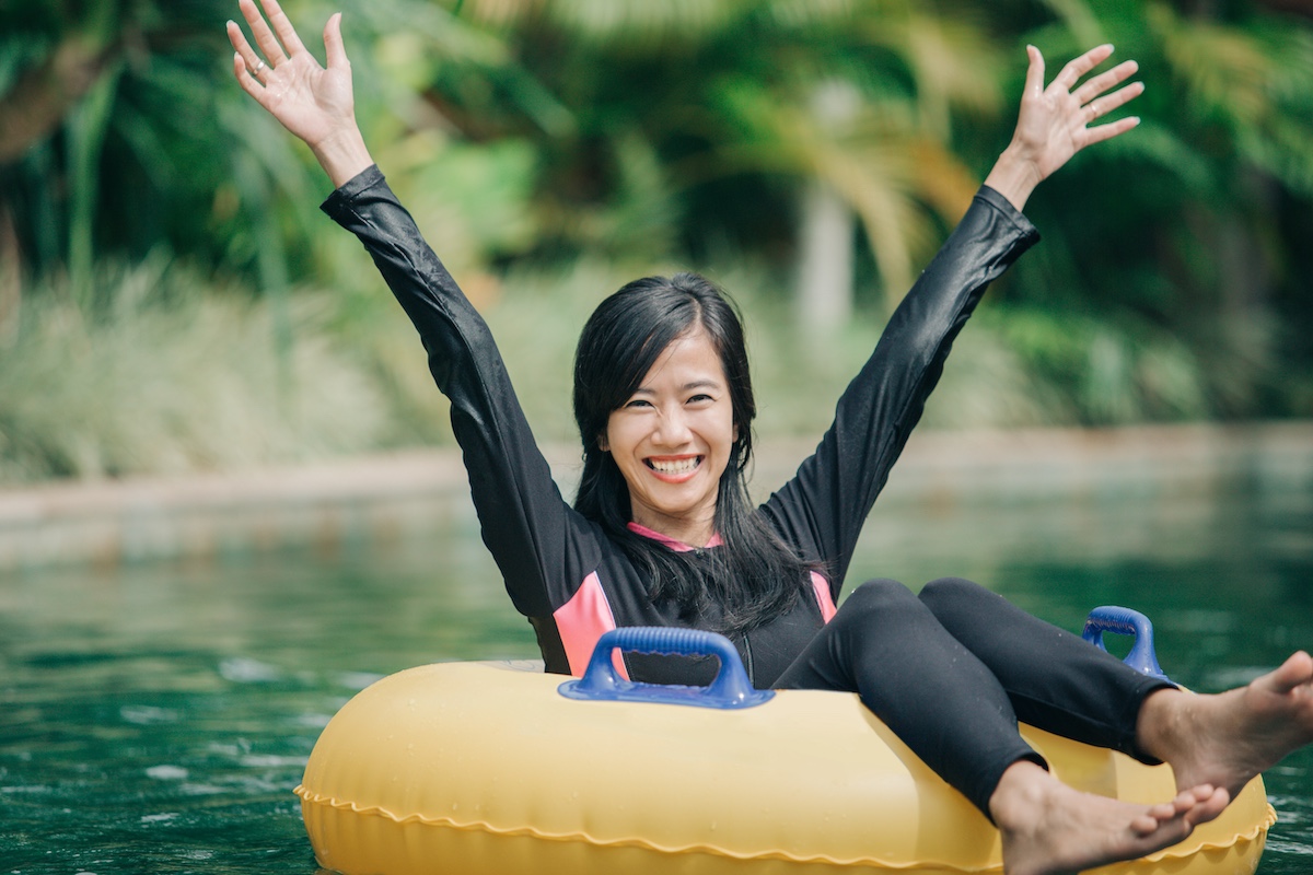 portrait of excited young woman raised her arm enjoy tubing at lazy river pool